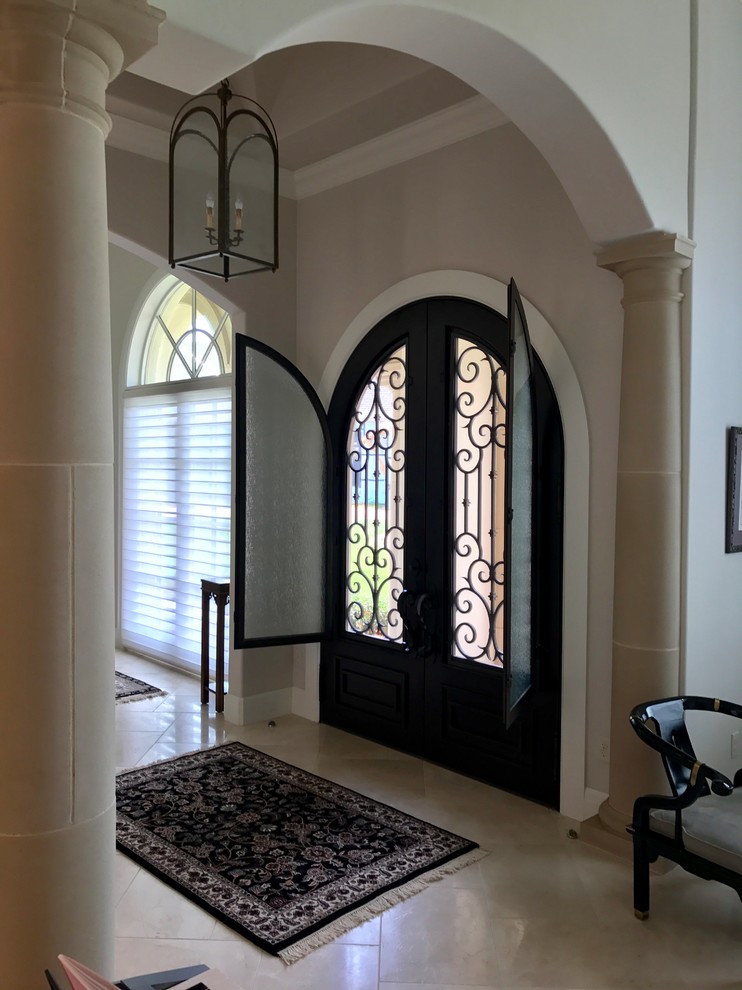 На фото: входная дверь среднего размера в стиле неоклассика (современная классика) с бежевыми стенами, полом из травертина, двустворчатой входной дверью и бежевым полом с