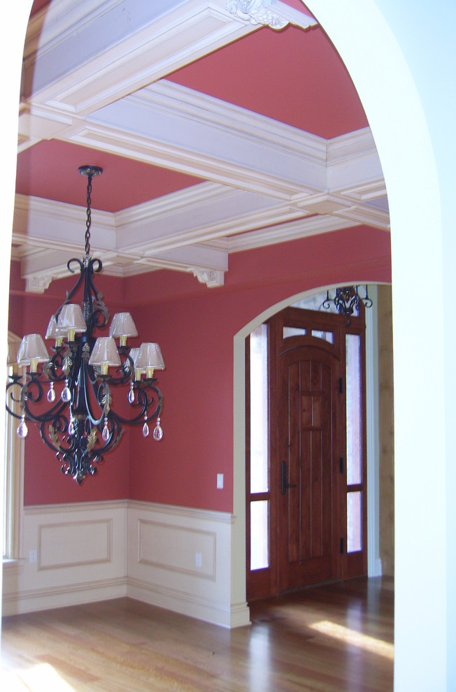 Diseño de puerta principal tradicional de tamaño medio con paredes rojas, suelo de madera clara, puerta simple, puerta de madera oscura y suelo marrón