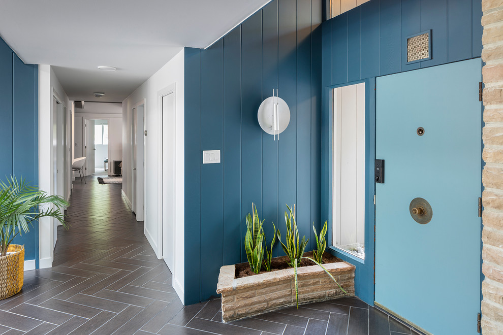 Immagine di un corridoio minimalista con pareti blu, una porta singola, una porta blu e pavimento marrone