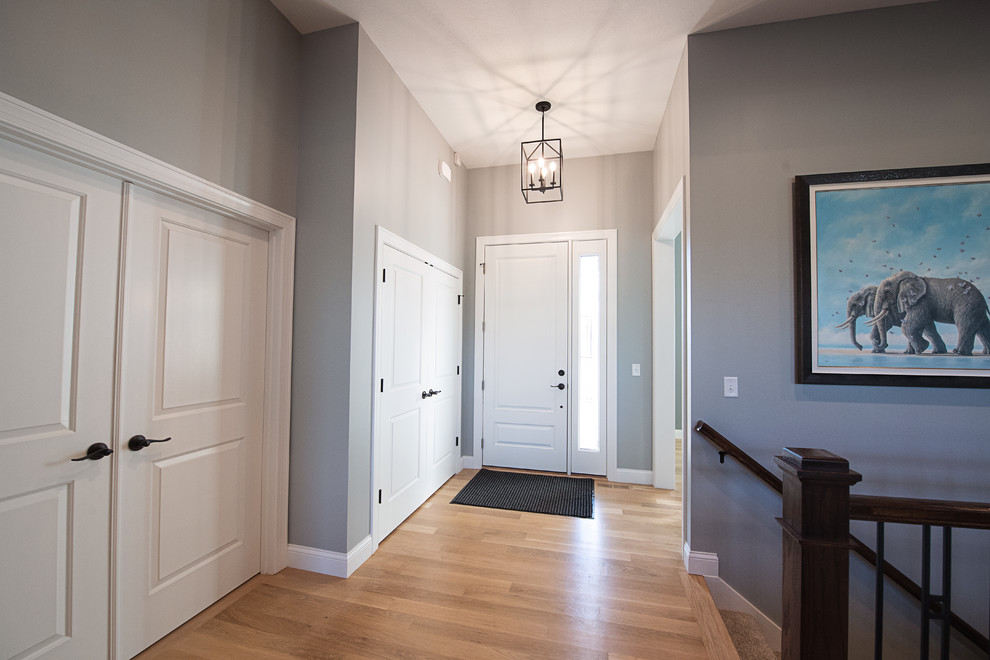 他の地域にあるトラディショナルスタイルのおしゃれな玄関ロビー (グレーの壁、淡色無垢フローリング、白いドア、白い床) の写真