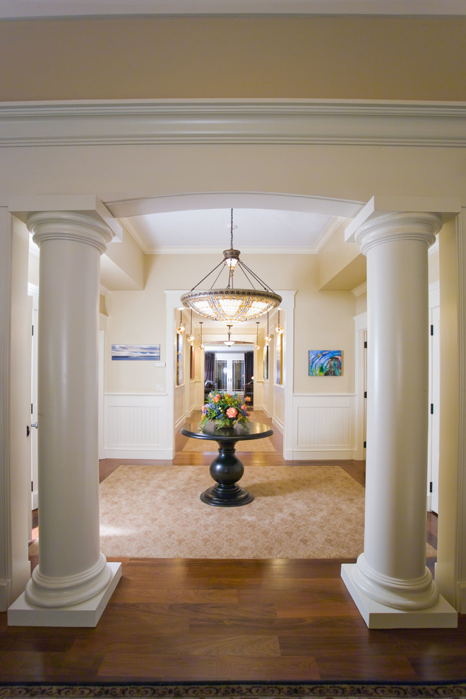 Cette image montre un hall d'entrée traditionnel avec un mur beige et un sol en bois brun.