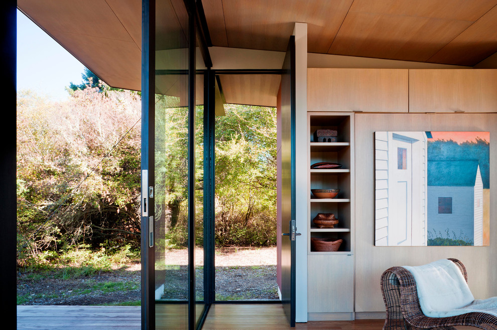 Inspiration pour une petite porte d'entrée minimaliste avec un mur marron, un sol en bois brun, une porte simple et une porte noire.