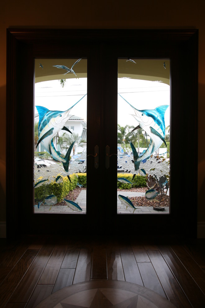 Aménagement d'une porte d'entrée bord de mer avec parquet foncé, une porte double et une porte en verre.