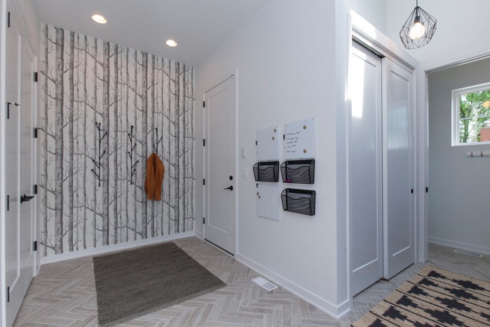 Idee per un grande ingresso con vestibolo minimalista con pareti bianche, pavimento in gres porcellanato, pavimento grigio e carta da parati