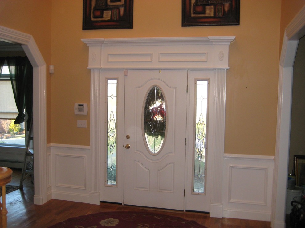 Idee per un ingresso classico di medie dimensioni con pareti gialle, pavimento in legno massello medio, una porta singola, una porta in legno scuro e pavimento marrone