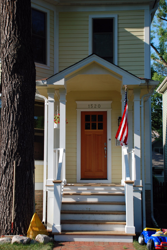 На фото: входная дверь среднего размера в стиле кантри с одностворчатой входной дверью, входной дверью из дерева среднего тона и желтыми стенами
