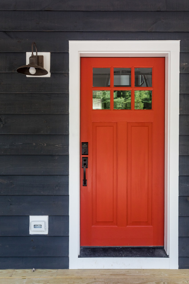 Foto på en lantlig entré, med en enkeldörr och en röd dörr