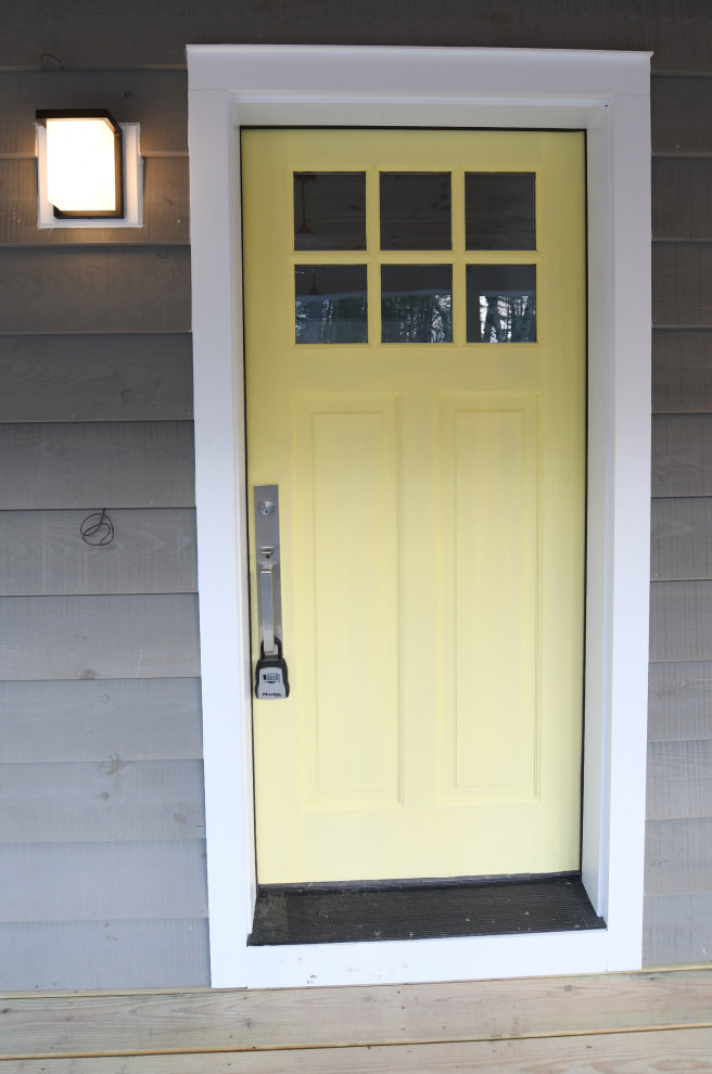 Aménagement d'une porte d'entrée campagne de taille moyenne avec un mur gris, parquet clair, une porte simple et une porte jaune.