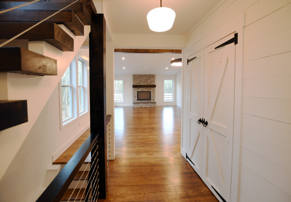 Imagen de hall campestre de tamaño medio con paredes blancas, suelo de madera en tonos medios, puerta simple, puerta amarilla, suelo marrón y machihembrado