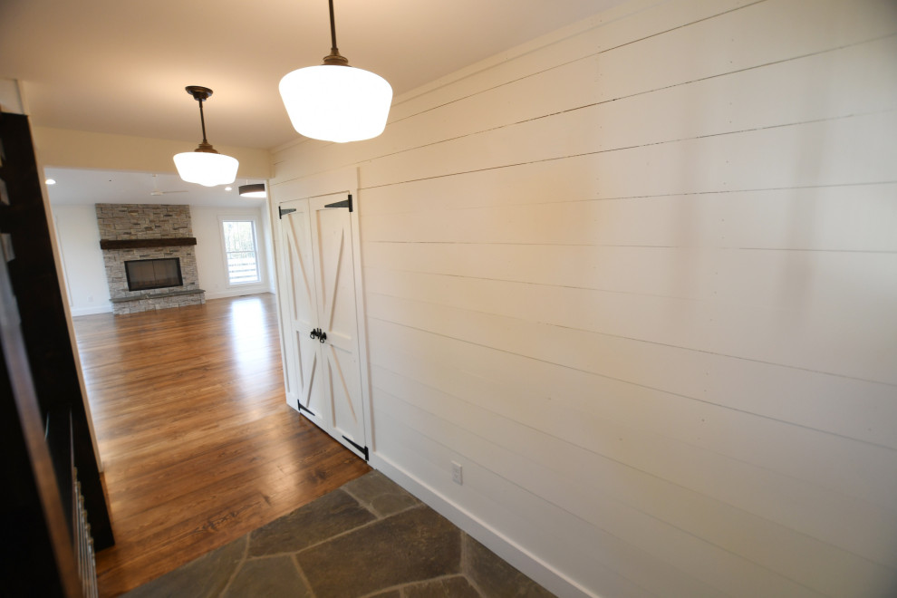 Mittelgroßer Landhausstil Eingang mit Korridor, weißer Wandfarbe, braunem Holzboden, Einzeltür, gelber Haustür, braunem Boden und Holzdielenwänden in New York