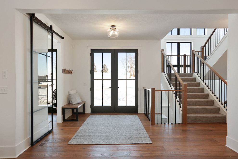 Imagen de distribuidor de estilo de casa de campo extra grande con paredes grises, suelo de madera en tonos medios, puerta doble y puerta de vidrio