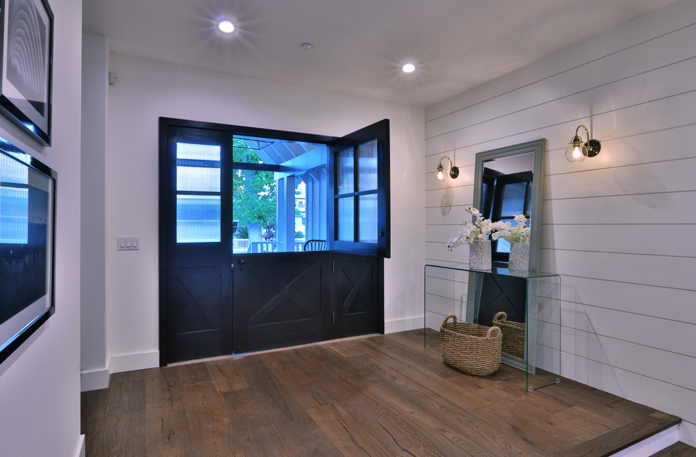 Country Foyer mit weißer Wandfarbe, braunem Holzboden, Klöntür und schwarzer Haustür in Los Angeles