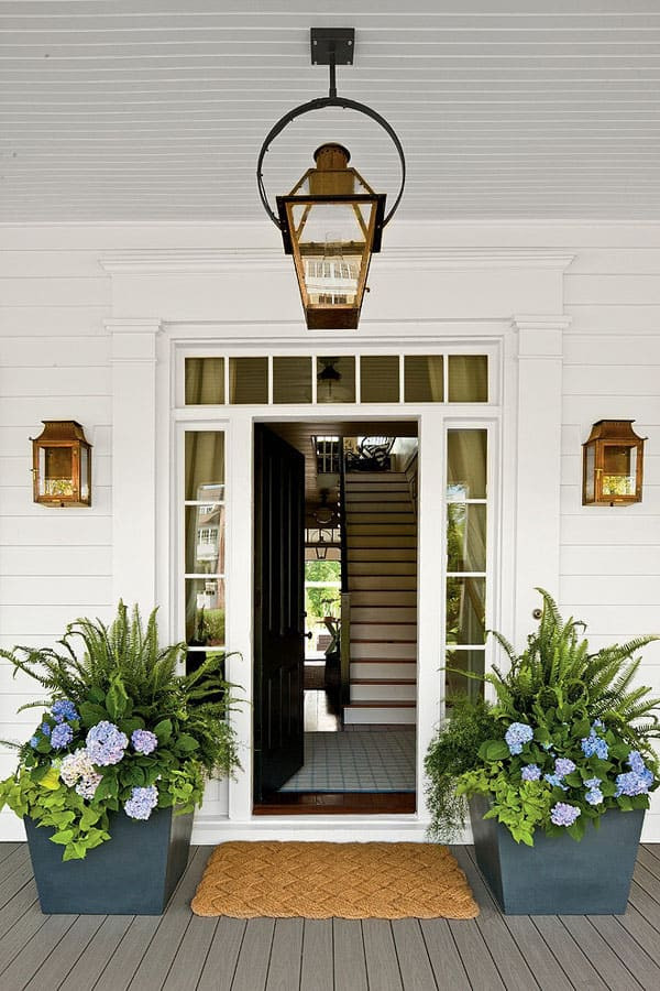 Modelo de puerta principal de estilo de casa de campo grande con paredes blancas, suelo de madera en tonos medios, puerta simple y puerta negra