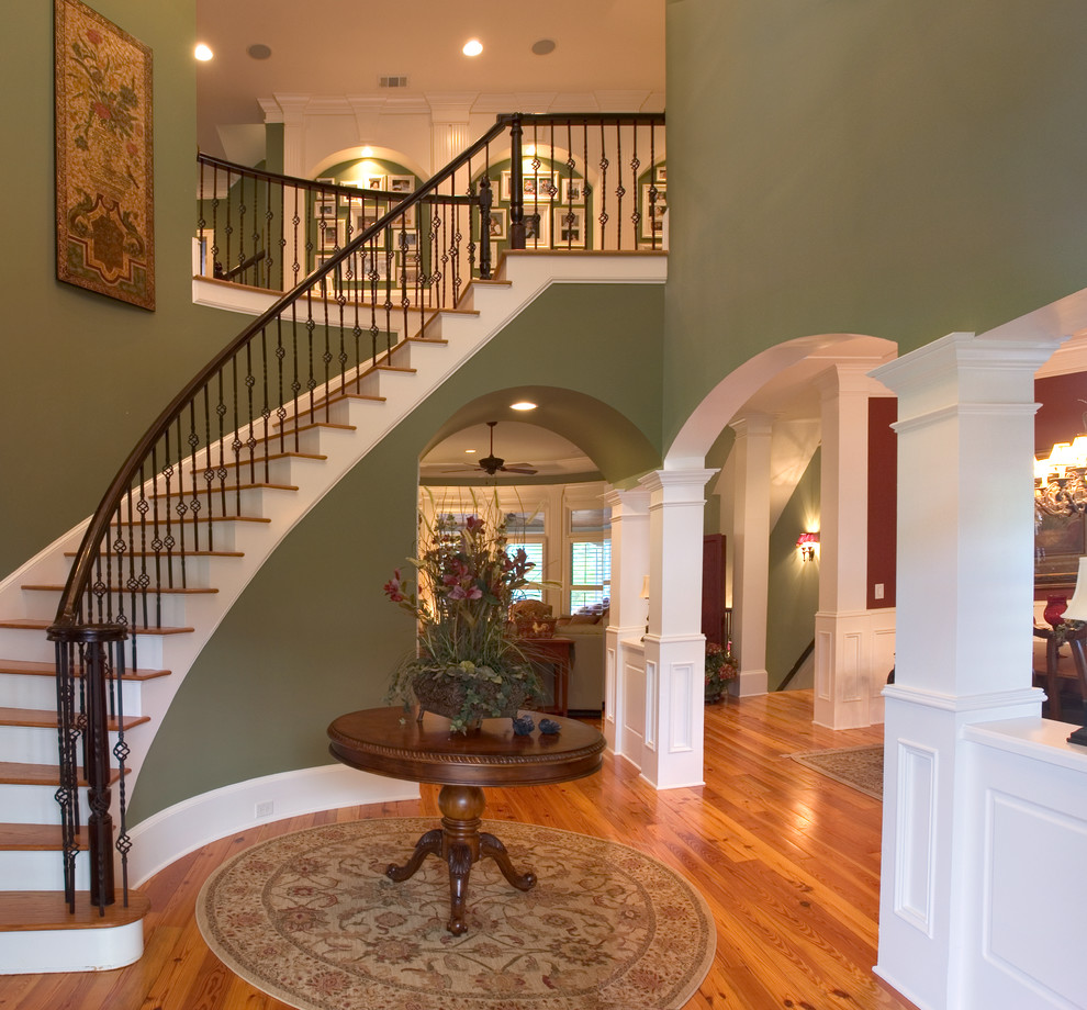 Großes Landhausstil Foyer mit grüner Wandfarbe, braunem Holzboden, Drehtür und Haustür aus Glas in Atlanta