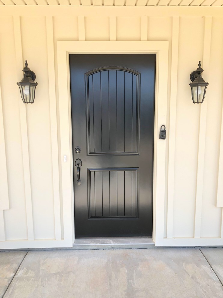 Ejemplo de puerta principal de estilo de casa de campo grande con paredes grises, suelo de cemento, puerta simple, puerta negra y suelo gris