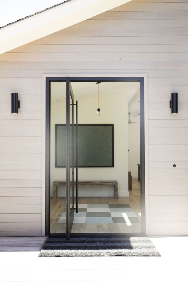 Immagine di una porta d'ingresso country di medie dimensioni con pareti beige, una porta a pivot e una porta in vetro