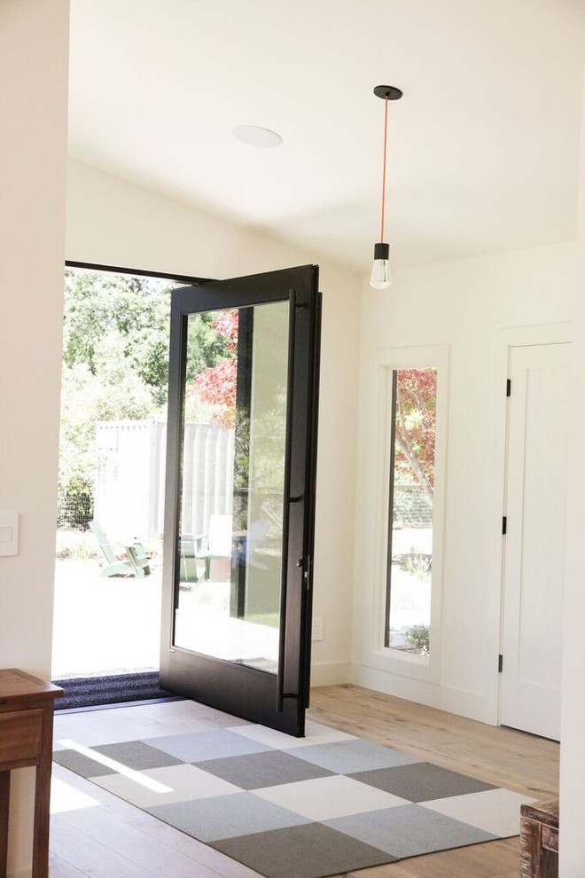 Design ideas for a medium sized rural front door in San Francisco with white walls, light hardwood flooring, a pivot front door, a glass front door and beige floors.