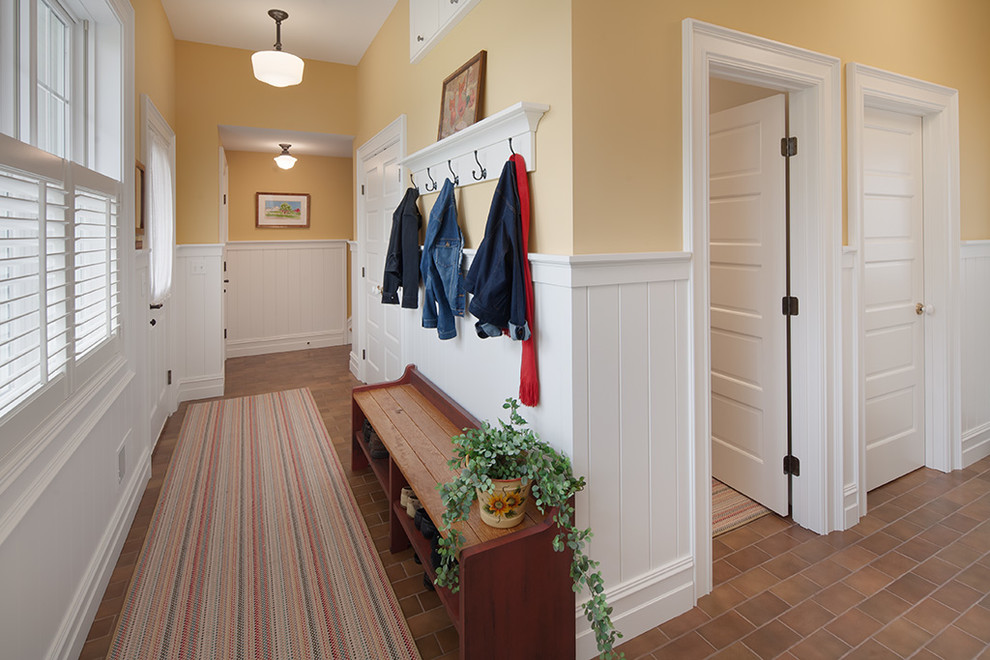 Источник вдохновения для домашнего уюта: большой тамбур в стиле кантри с желтыми стенами, кирпичным полом и одностворчатой входной дверью