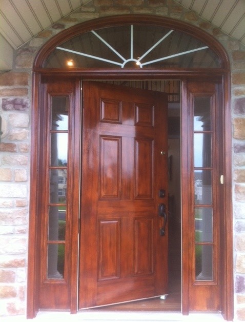 Cette image montre une porte d'entrée traditionnelle avec une porte simple et une porte en bois brun.
