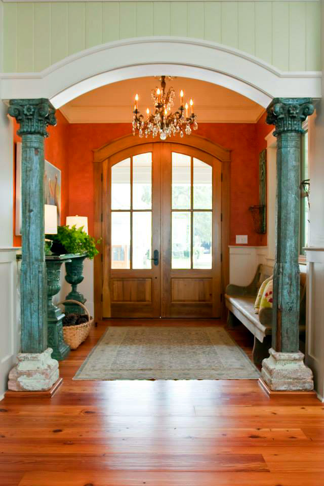 Klassisk inredning av en mellanstor ingång och ytterdörr, med orange väggar, mellanmörkt trägolv, en dubbeldörr och ljus trädörr