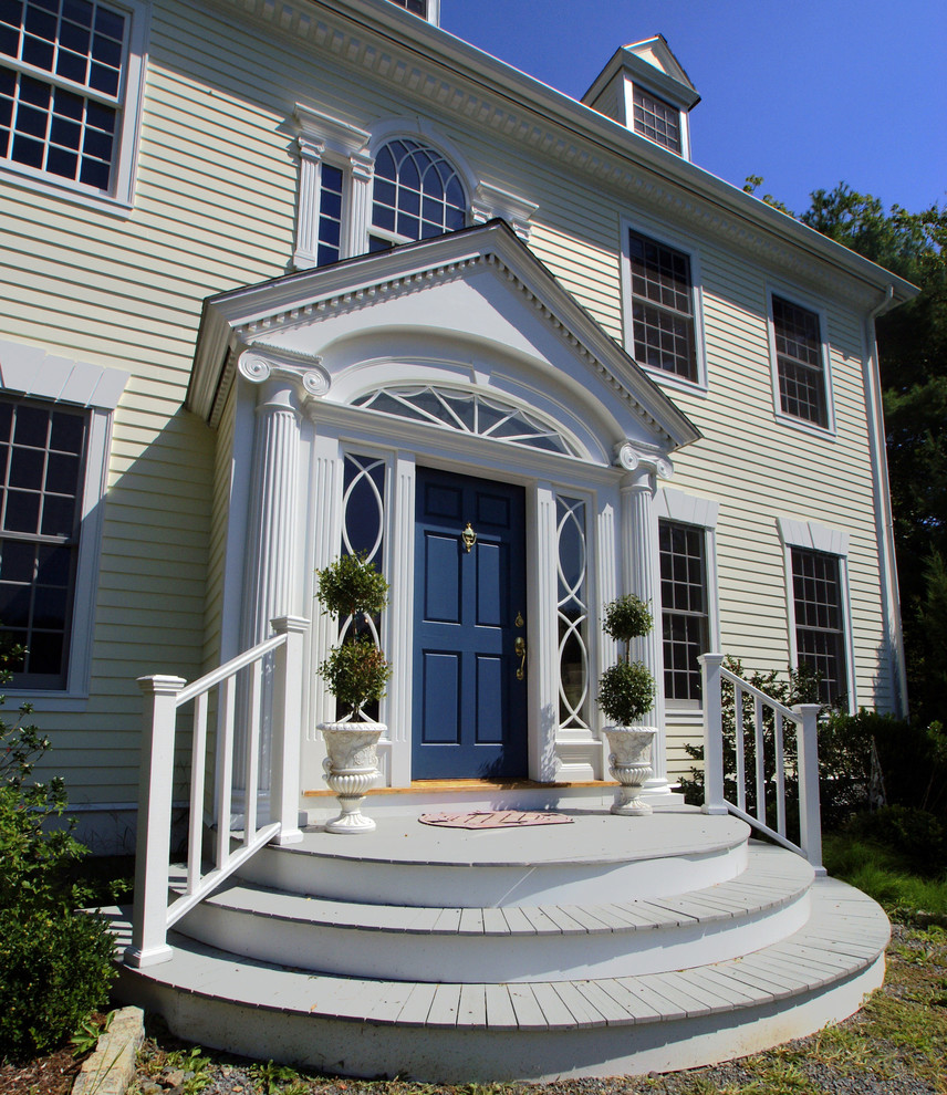 Große Klassische Haustür mit gelber Wandfarbe, braunem Holzboden, Einzeltür und blauer Haustür in Boston