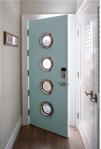Esempio di una porta d'ingresso costiera di medie dimensioni con pareti beige, pavimento in legno massello medio, una porta singola, una porta blu e pavimento marrone