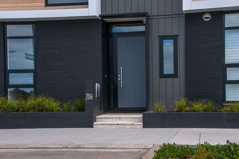 Cette photo montre une porte d'entrée moderne avec un mur multicolore, une porte simple et une porte grise.