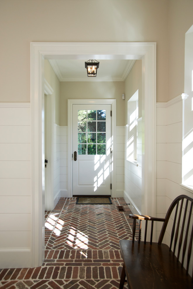 Inspiration pour une entrée traditionnelle avec un vestiaire, un mur beige, un sol en brique, une porte simple et une porte blanche.