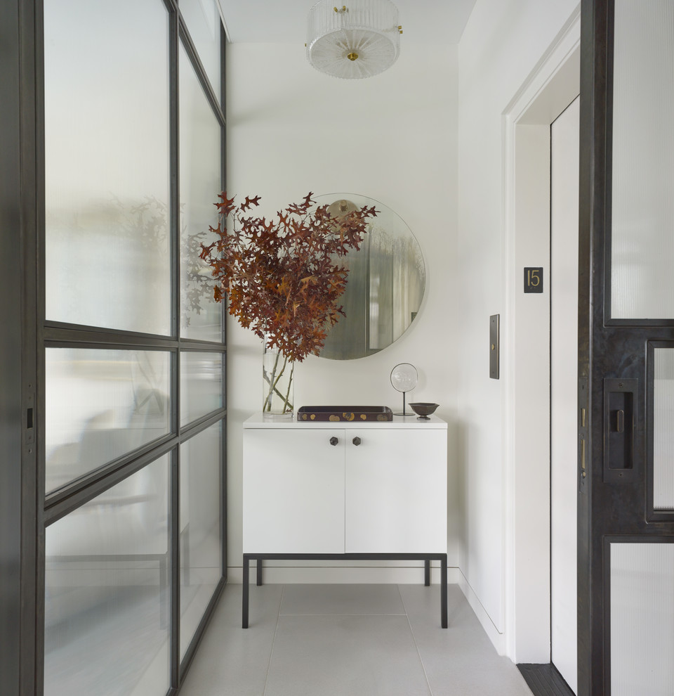 На фото: маленькое фойе в стиле модернизм с белыми стенами, бетонным полом, черной входной дверью и серым полом для на участке и в саду с