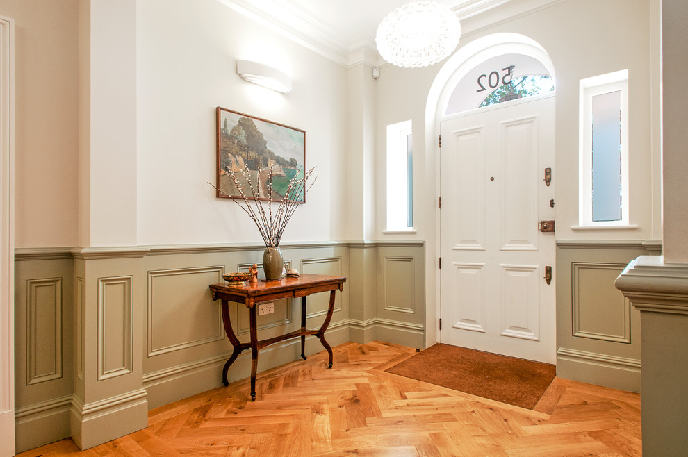 Entryway - traditional medium tone wood floor and brown floor entryway idea in London with a white front door and white walls