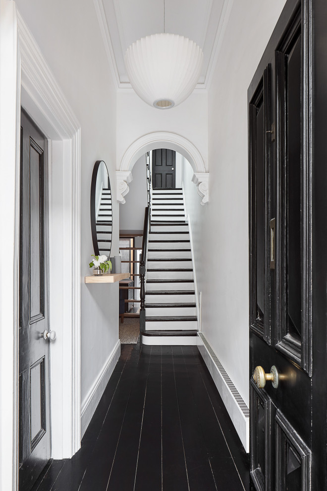 This is an example of a large contemporary hallway in Melbourne with white walls, a single front door, a black front door and black floors.