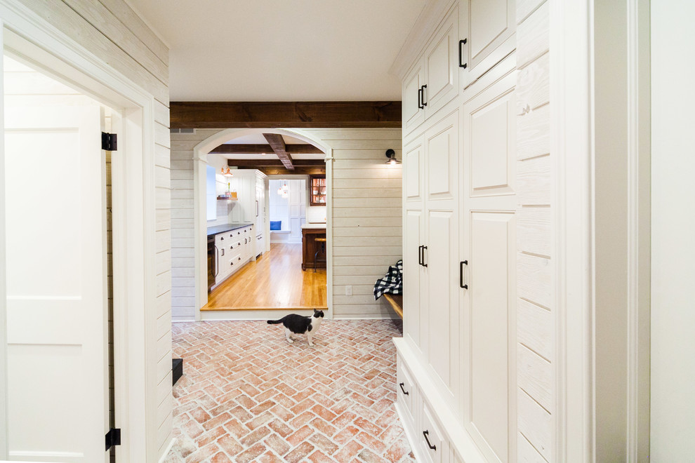 На фото: большой тамбур в стиле кантри с белыми стенами, кирпичным полом, одностворчатой входной дверью, серой входной дверью и разноцветным полом с