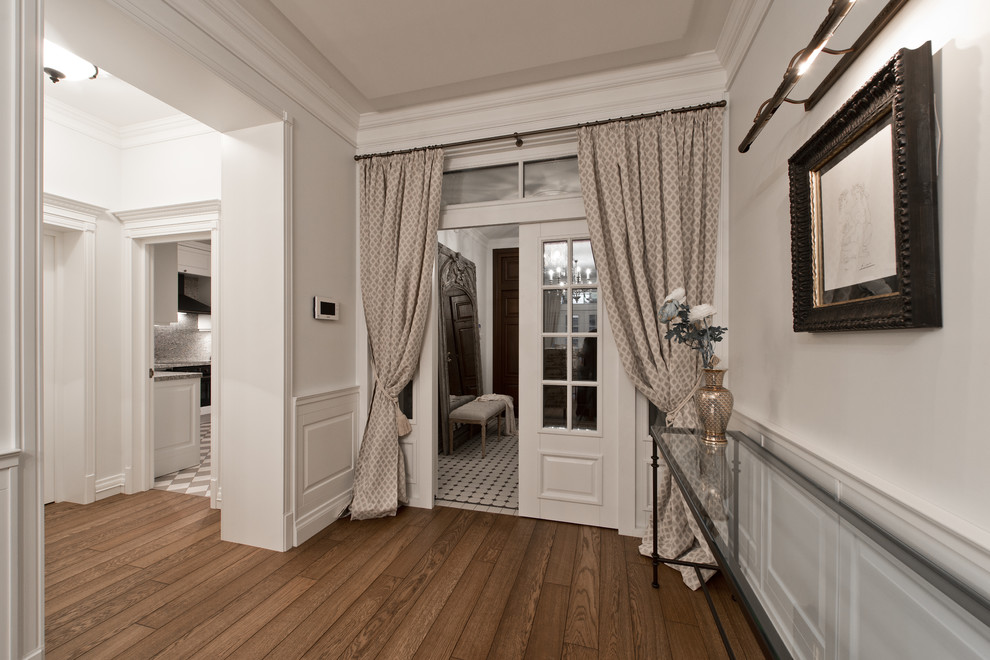 Esempio di un corridoio tradizionale di medie dimensioni con pareti bianche, pavimento in legno verniciato, una porta a due ante e una porta bianca