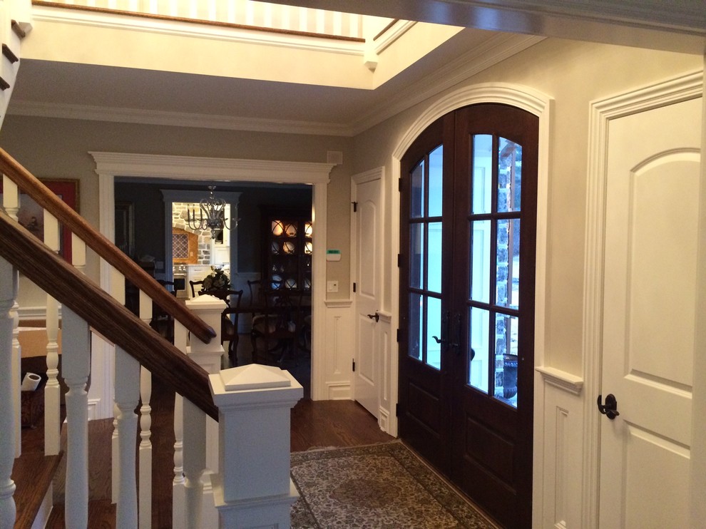 Idee per un grande ingresso chic con pareti beige, pavimento in legno massello medio, una porta a due ante e una porta in legno scuro