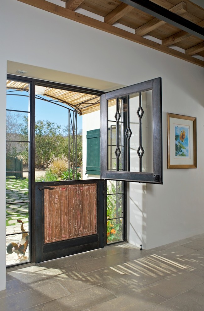This is an example of a country front door in Other with white walls, concrete flooring, a stable front door and a metal front door.