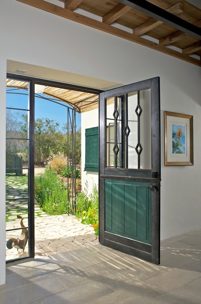 На фото: входная дверь среднего размера в стиле кантри с белыми стенами, бетонным полом, голландской входной дверью и металлической входной дверью с