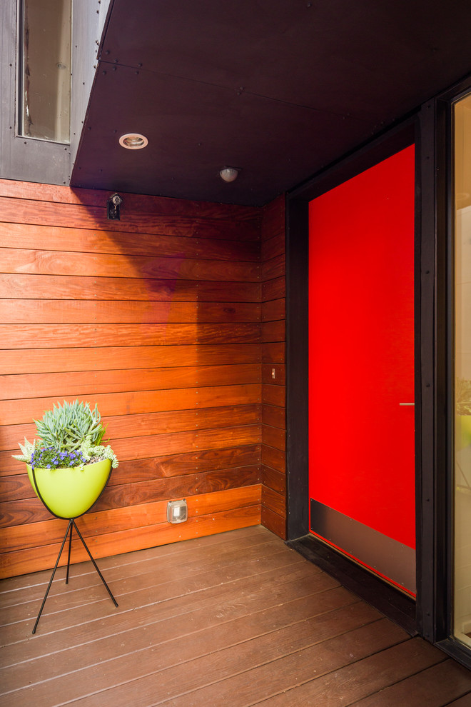 Idée de décoration pour une entrée design avec une porte rouge.