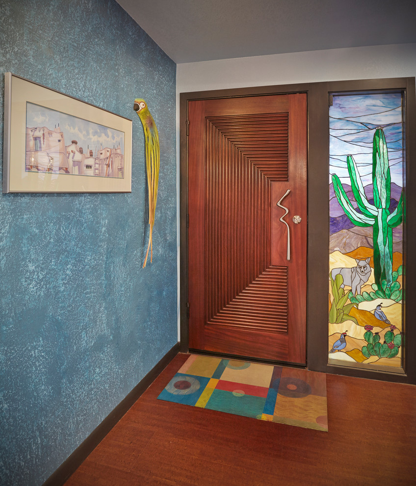 This is an example of a bohemian front door in Phoenix with blue walls, medium hardwood flooring, a single front door, a medium wood front door, brown floors and a feature wall.