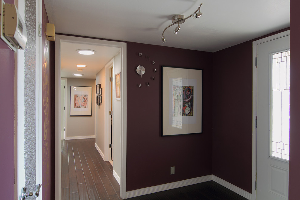 Cette photo montre un hall d'entrée tendance de taille moyenne avec une porte simple, une porte blanche, un mur violet et parquet foncé.
