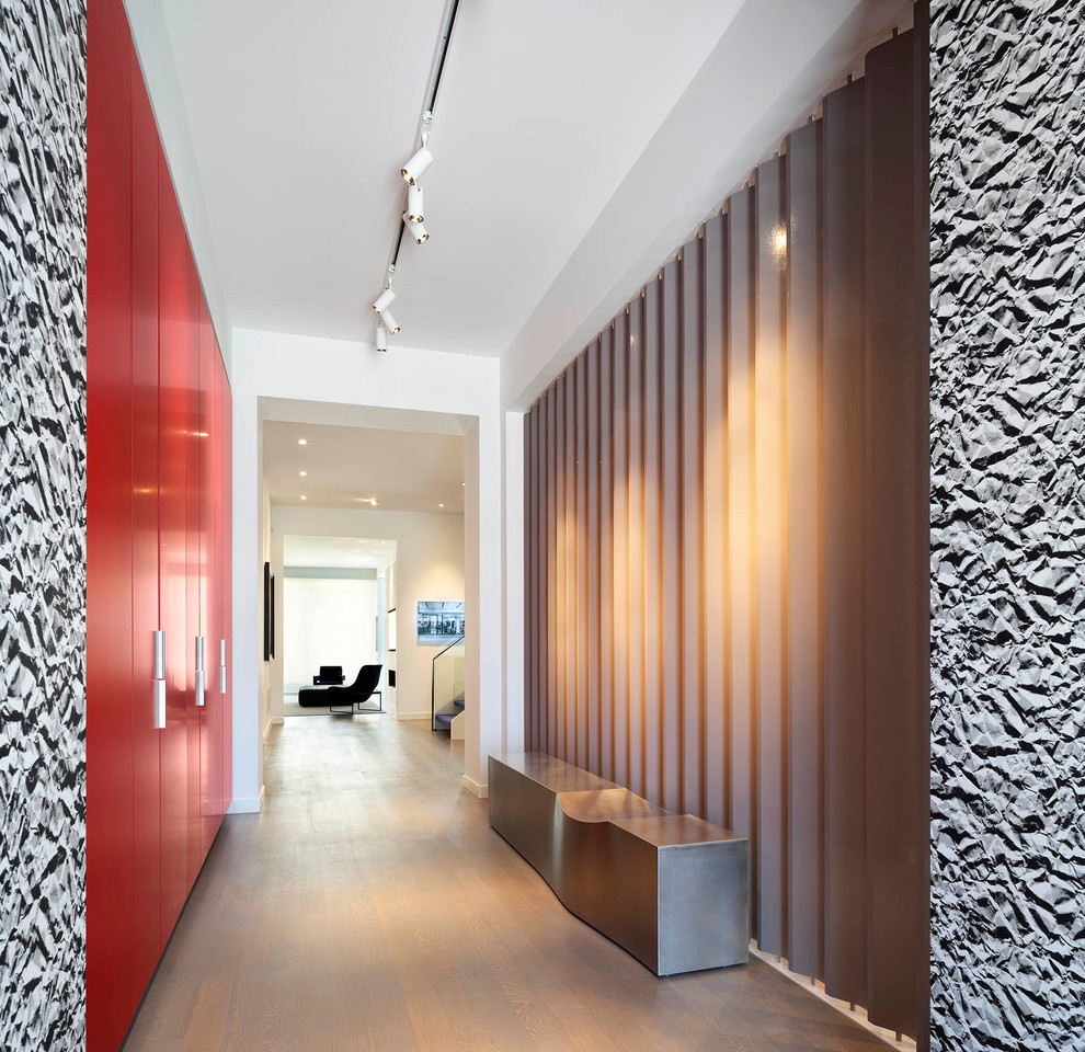 Idee per un grande ingresso moderno con pareti bianche e pavimento in legno massello medio