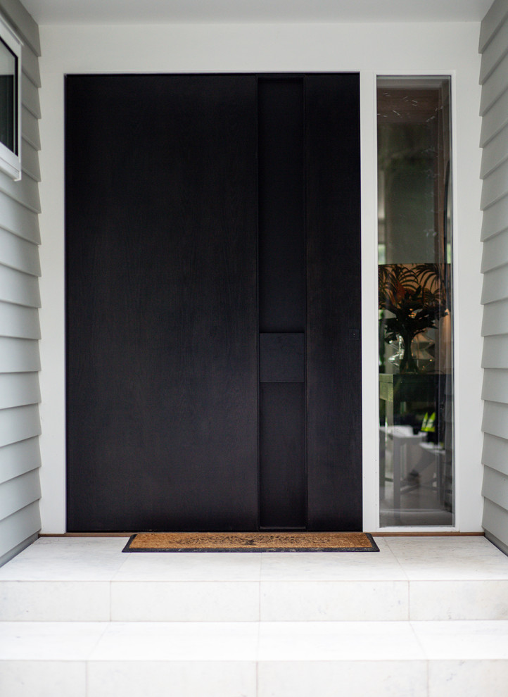 Cette photo montre une porte d'entrée tendance avec un mur gris, un sol en carrelage de porcelaine, une porte noire et un sol gris.