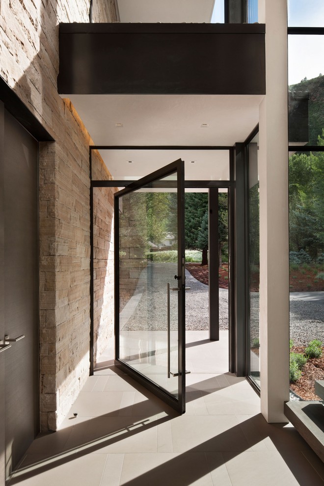 Ispirazione per un corridoio moderno con una porta a pivot, una porta in vetro e pavimento marrone