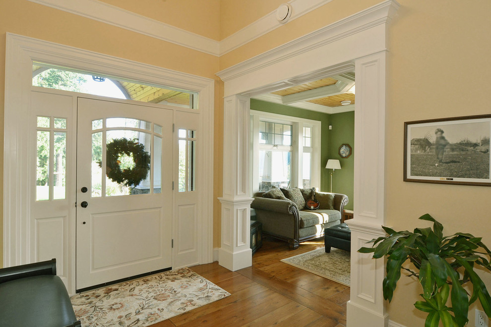 Aménagement d'un hall d'entrée craftsman de taille moyenne avec un mur vert, parquet foncé, une porte double et une porte en bois foncé.