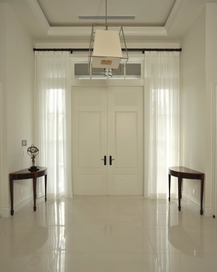 Immagine di una porta d'ingresso minimal di medie dimensioni con pareti bianche, pavimento in marmo, una porta a due ante, una porta bianca e pavimento beige