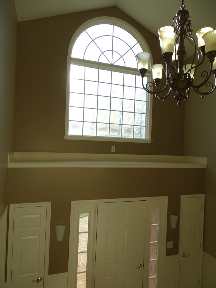 Пример оригинального дизайна: большое фойе в классическом стиле с бежевыми стенами, темным паркетным полом, одностворчатой входной дверью, металлической входной дверью, коричневым полом и панелями на стенах