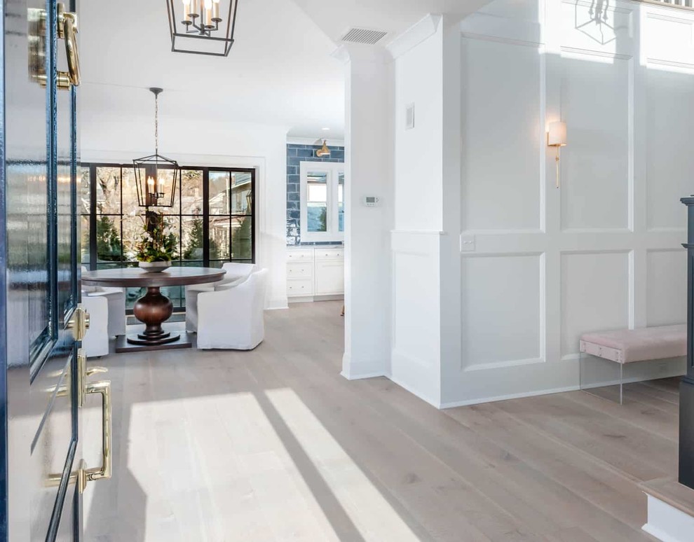 Example of a mid-sized beach style light wood floor and brown floor entryway design in New York with white walls and a glass front door