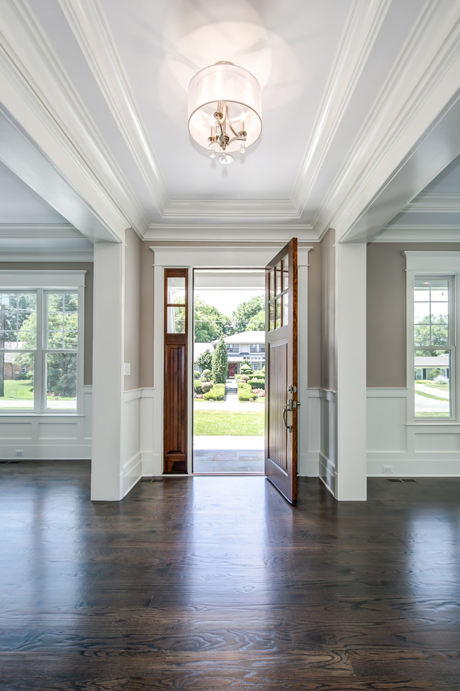 Aménagement d'un hall d'entrée classique de taille moyenne avec un mur gris, parquet foncé, une porte simple et une porte en bois brun.