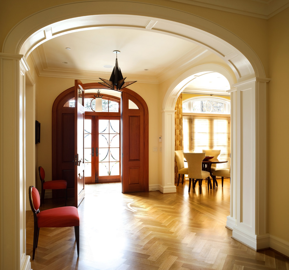 Immagine di un corridoio design con pavimento in legno massello medio, una porta a due ante e una porta in vetro