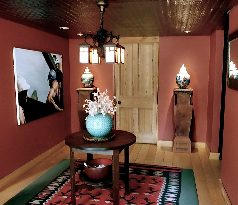 Idée de décoration pour un hall d'entrée bohème de taille moyenne avec un mur rouge, parquet clair et une porte simple.