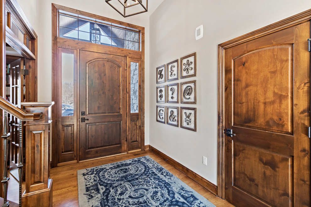 Inspiration pour une porte d'entrée chalet de taille moyenne avec un mur beige, un sol en bois brun, une porte simple, une porte en bois foncé et un sol marron.